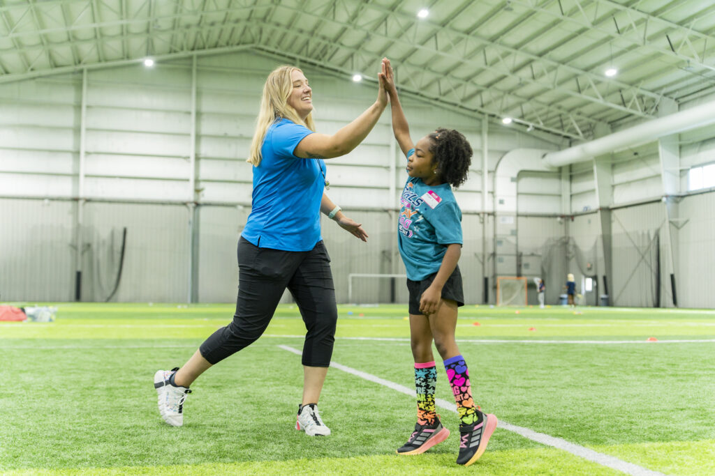 Young girl and coach high-fiving.