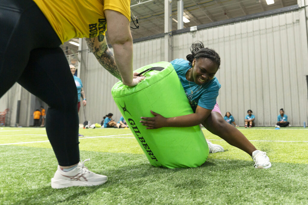Young girl tackling a bag while playing rugby.